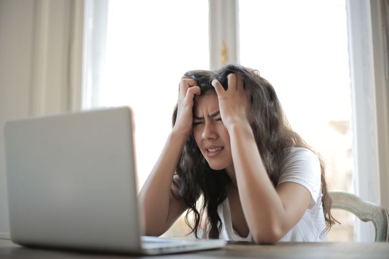 Problems - woman holding her hair in front of a laptop