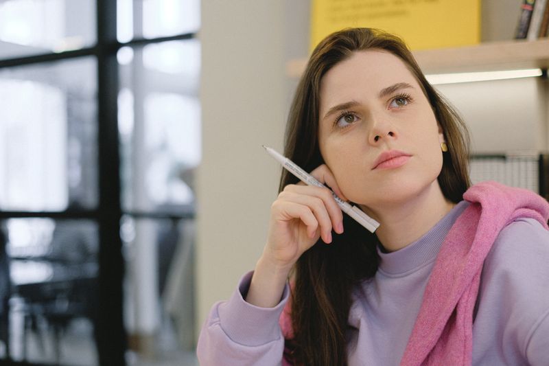 Woman thinking while holding a pen